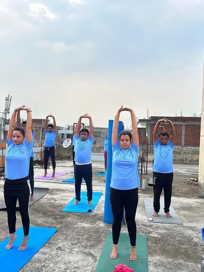 Students practicing Tadasana (Mountain Pose) with arms raised during our rooftop yoga session. Practicing outdoors adds a different energy to the asanas.