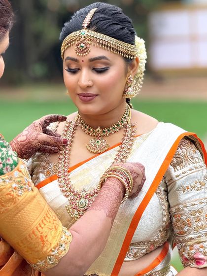 A touching moment as the bride gets her final jewelry adjustments. The makeup is soft and elegant, perfect for these heartfelt moments.