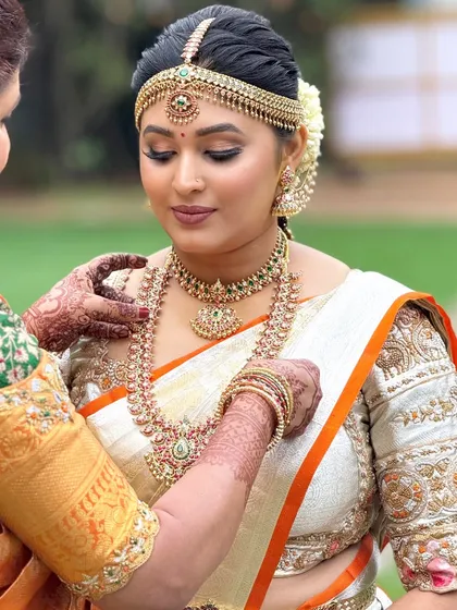 A touching moment as the bride gets her final jewelry adjustments. The makeup is soft and elegant, perfect for these heartfelt moments.