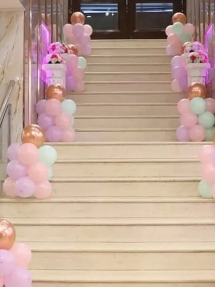 Elegant staircase decoration with pastel balloon pillars topped with rose gold balloons.