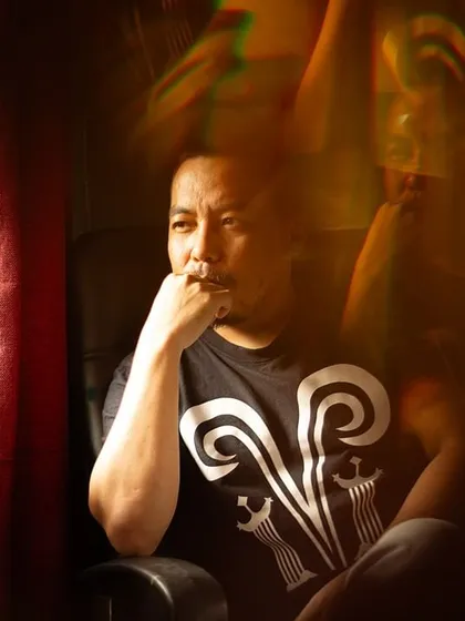 An atmospheric color portrait of tattoo artist Mo Naga in a moment of contemplation, with creative light flares adding to the mood. This image shows my approach to capturing the personality of professionals and artists.