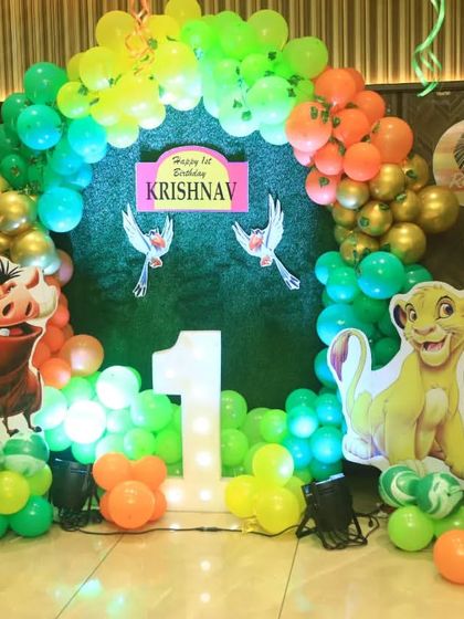 We created a Lion King theme for this first birthday, featuring a grass-like backdrop and cutouts of Simba, Timon, and Pumbaa. The balloon arch in green, yellow, and orange mimics a jungle sunrise.