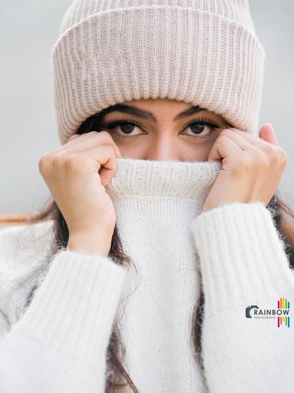 A cozy winter-themed portrait. The way the model peeks over the sweater creates a sense of mystery and draws attention to her eyes.