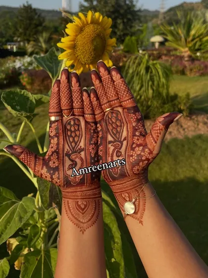 A beautiful shot of the rich henna stain against a sunflower, showcasing a simple yet elegant design perfect for any celebration.