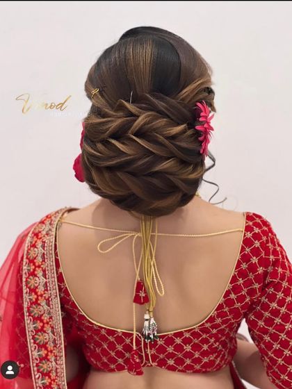 A close-up of the finished traditional low bun, highlighting the texture from the interwoven braids and the pop of color from the flowers.