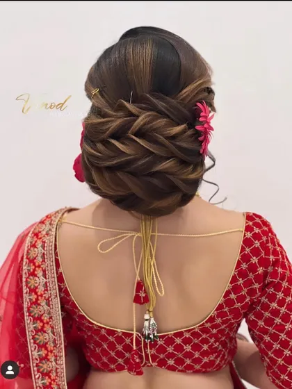 A close-up of the finished traditional low bun, highlighting the texture from the interwoven braids and the pop of color from the flowers.