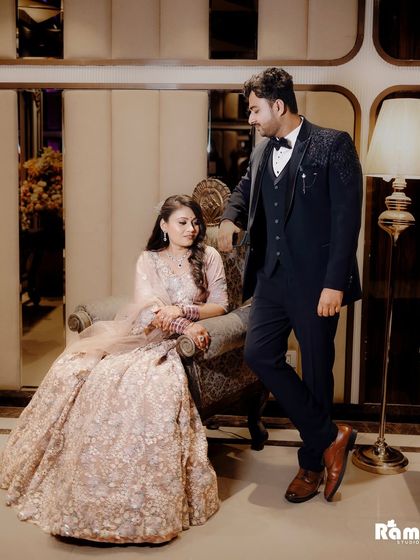 A stylish portrait of the couple, with the bride seated and the groom standing beside her. The composition and their poses create a look of classic romance.