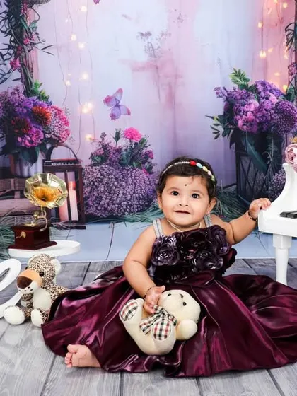 A wider view of the enchanting purple piano set. The soft lighting and fairytale-like background elements come together to create a truly memorable first birthday photograph.