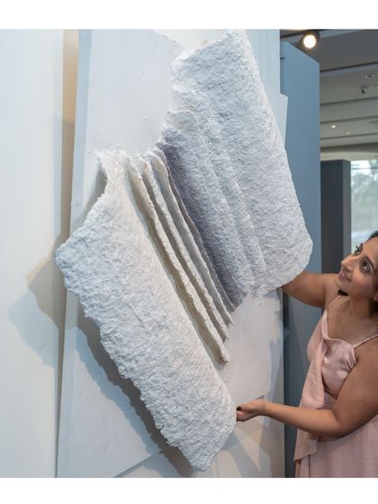 Adjusting "The Flight of Knowledge." The piece is made from upcycled paper, giving it a beautifully raw and textured feel, like the pages of an ancient book.