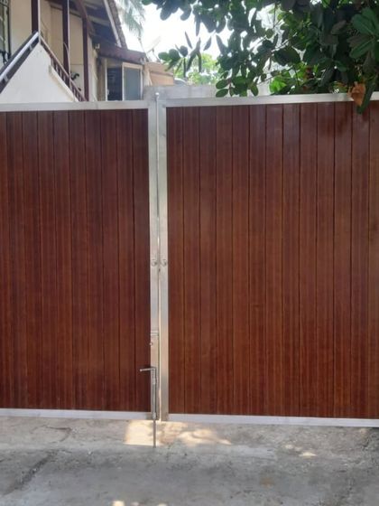 A classic swing gate design using vertical wood-finish panels and a stainless steel frame. This combination of materials is both timeless and highly durable.