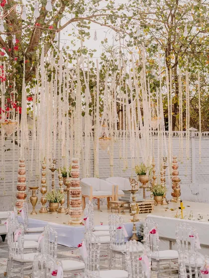The beautiful wedding mandap, decorated with hanging white florals and traditional brass elements, ready for the ceremony.