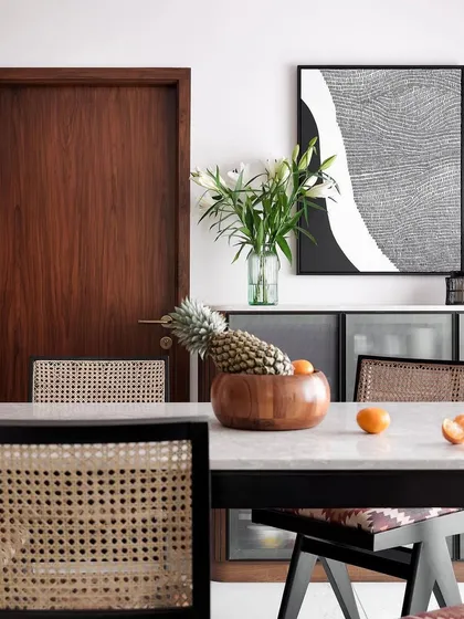 A close-up of my Pierre Jeanneret-inspired chairs around a marble-topped dining table in a client's home.