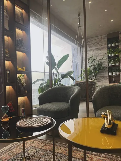 I call this the art of modern comfort. This corner of a contemporary home features plush seating, a curated bookshelf, and a seamless connection to the outdoor balcony, creating a perfect space for relaxation.
