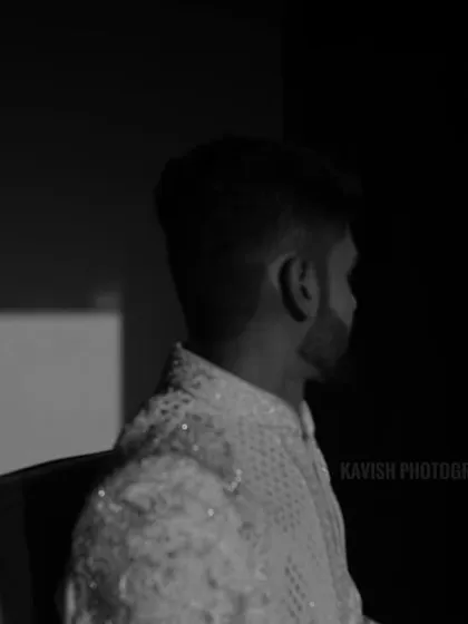 An artistic black and white shot of the groom, playing with his shadow projected on the wall.