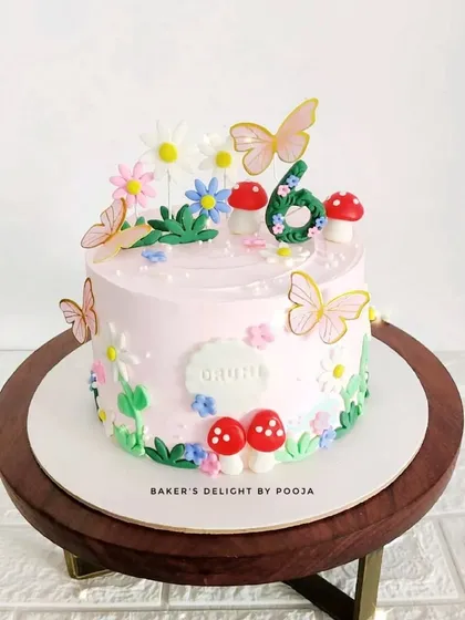 An enchanted floral cake for a 6th birthday. This dreamy pink cake is decorated with butterflies, mushrooms, and hand-piped flowers, creating a magical garden scene.