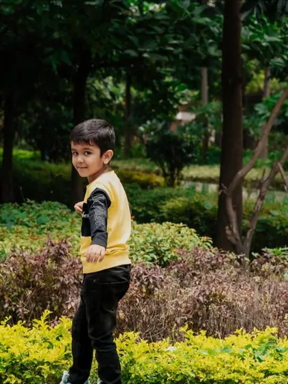 Capturing a child's playful energy as he looks back with a smile during our outdoor photoshoot in a lush Bangalore park.