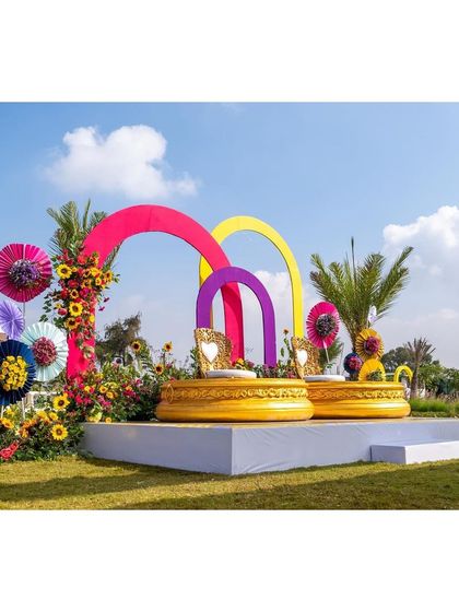 A side view of the Haldi stage, showcasing the layered colorful arches and whimsical paper fan decorations.