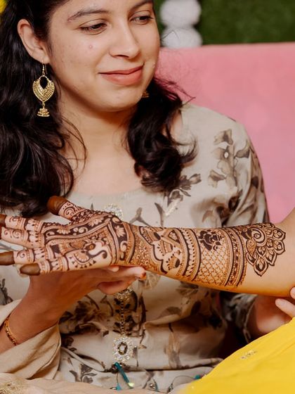 A client admiring the intricate details of her bridal mehendi. These quiet moments are just as special.
