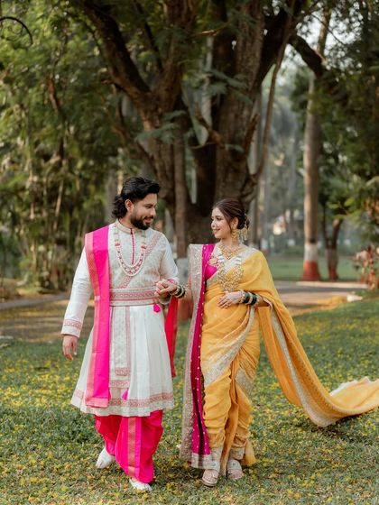 A lovely couple shot, showcasing the groom's coordinated outfit and the bride's stunning yellow Nauvari saree and traditional hairstyle.