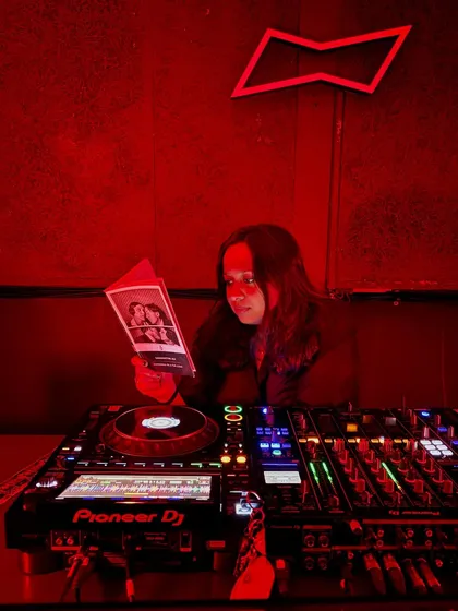 In the zone, surrounded by red light and the tools of my trade. This is my happy place, digging for tracks and getting ready to take the dancefloor on a journey. I'm a performative, charismatic disc jockey, available for bookings worldwide.