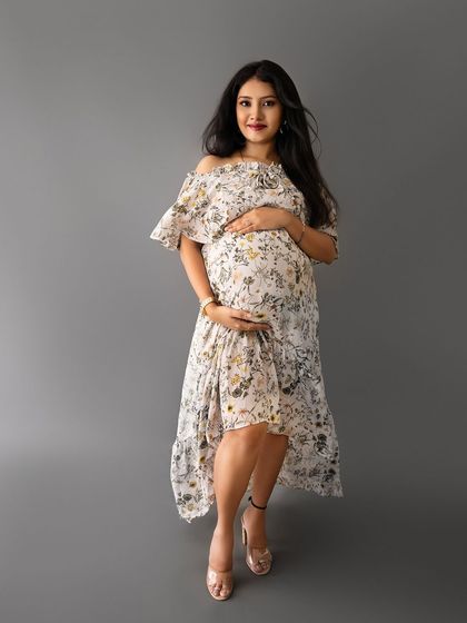 A full-length portrait of a mom-to-be in a lovely floral print dress, showcasing a fresh and casual maternity look.