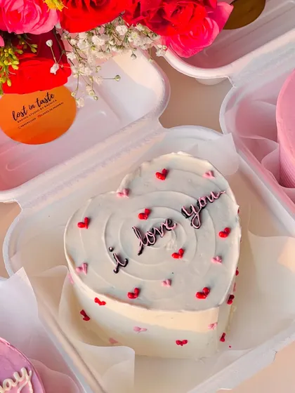 An "I love you" message on a heart-shaped bento cake, decorated with both red and pink hearts for a romantic and sweet declaration.