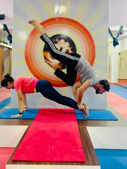 This advanced acro yoga pose combines a plank from the base with a challenging arm balance from the flyer. It is a true test of strength, concentration, and partnership.