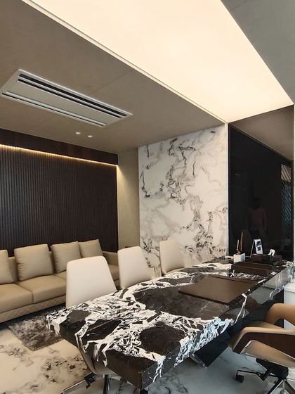 An alternate view of the executive office, showing the informal seating area alongside the main meeting table. This flexible layout provides space for both formal discussions and more relaxed conversations within a single, cohesive room.