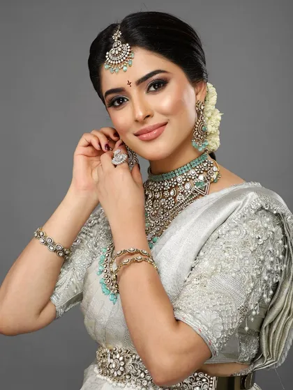 A candid moment of the client adjusting her earring, showcasing the beautiful details of her jewelry and the flawless makeup.