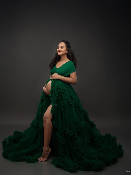 This emerald green gown makes a bold and beautiful statement. The high slit and ruffled train add a touch of glamour, perfect for a confident and stylish maternity portrait.