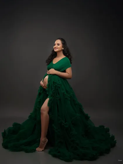 This emerald green gown makes a bold and beautiful statement. The high slit and ruffled train add a touch of glamour, perfect for a confident and stylish maternity portrait.