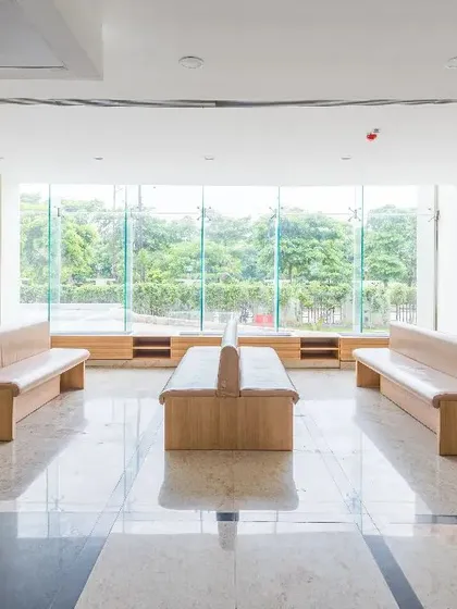 This waiting area at a Fortis facility is defined by its connection to the outdoors. A large window offers views of greenery, while the minimalist wooden benches and polished floors create a clean, tranquil space for reflection.