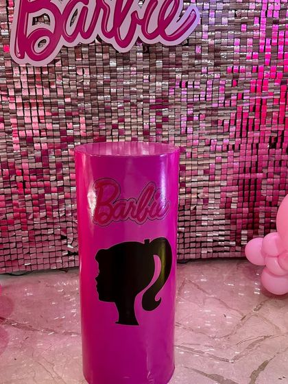 A close-up of a custom-branded pedestal with the iconic Barbie silhouette, used as part of the themed decor.