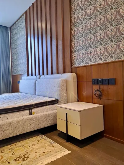 A close-up of the custom floating nightstand and upholstered bed, set against a rich backdrop of wood paneling and patterned wallpaper. Every detail is designed to create a luxurious and personalized environment.