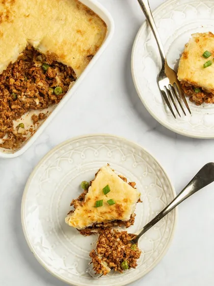This flat-lay of a plant-based shepherd's pie shows both the full dish and individual servings. The clean, bright styling makes the vegan comfort food look fresh, modern, and delicious.