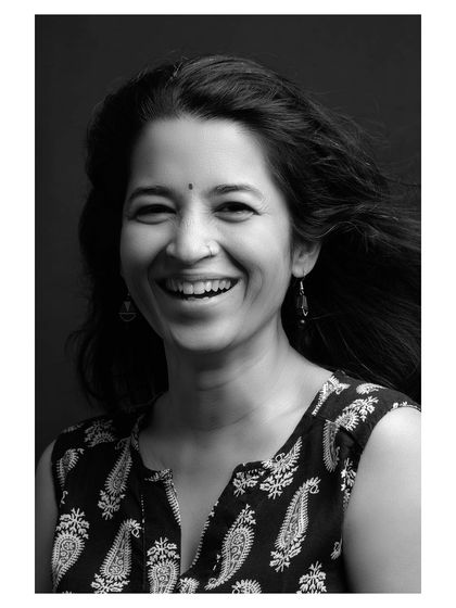A classic black and white studio portrait. The simple dark background and clean lighting focus entirely on the subject's warm and genuine smile.