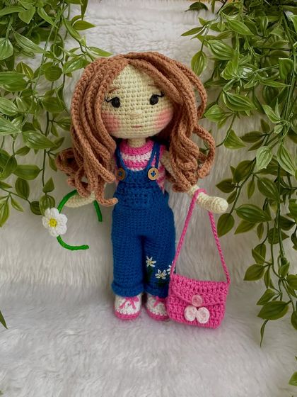 A closer look at the doll in her first outfit. The details on the overalls, like the little embroidered daisies, make her extra special. The clothes are designed to be easy for children to put on and take off.