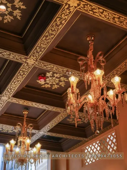 The ceiling is a fifth wall that deserves just as much attention. Here, we designed a dark wood coffered ceiling with intricate gold-painted floral patterns and hung opulent crystal chandeliers to create a truly grand and royal ambience.