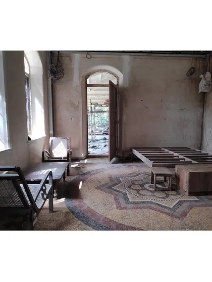 An interior space before our intervention, showing the beautiful but neglected china mosaic floor and bare walls. This serves as our starting point, a canvas from which we begin the careful process of adaptive reuse.
