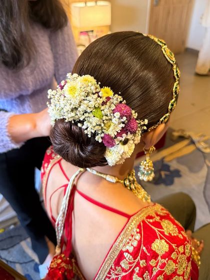 This dreamy floral bun features a mix of colorful fresh flowers like daisies and chrysanthemums. It's a vibrant and joyful style, perfect for a morning wedding ceremony.