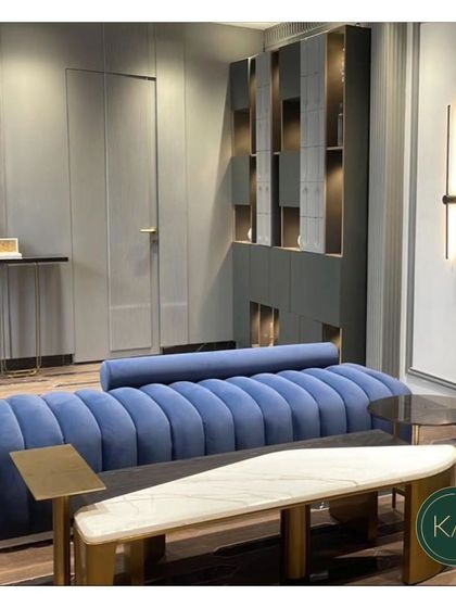 A stunning blue channel-tufted sofa serves as the focal point in this modern living area. We paired it with a unique bench-style coffee table and other bespoke storage solutions to create a cohesive and highly stylized space.