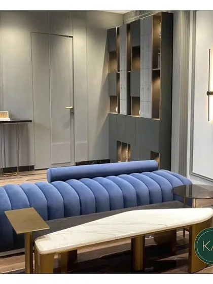 A stunning blue channel-tufted sofa serves as the focal point in this modern living area. We paired it with a unique bench-style coffee table and other bespoke storage solutions to create a cohesive and highly stylized space.