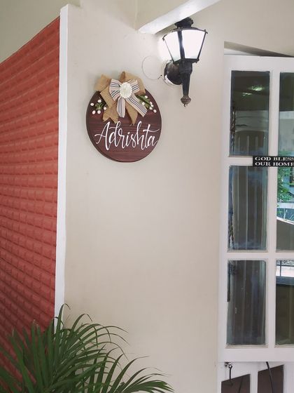 This beautiful round name plaque for "Adrishta" found its perfect spot. The dark wood stain, elegant calligraphy, and handmade burlap bow create a warm and welcoming entrance.