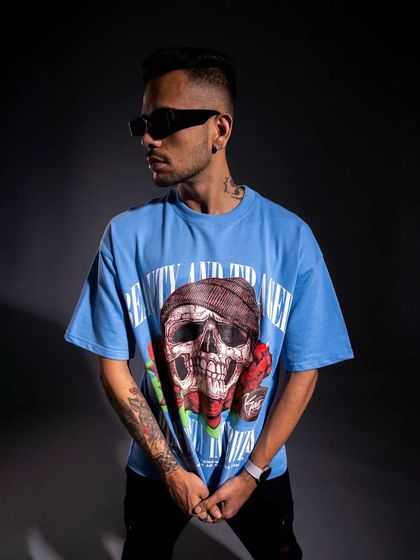 This shot showcases another graphic tee from the collection. The three-quarter turn and side lighting effectively display the tattoo art on the model's arm, adding to the edgy aesthetic.