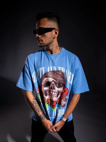 This shot showcases another graphic tee from the collection. The three-quarter turn and side lighting effectively display the tattoo art on the model's arm, adding to the edgy aesthetic.