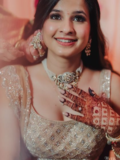 A happy bride showing off her gorgeous henna stain. The intricate jaali pattern with floral details looks exceptionally sharp and dark.
