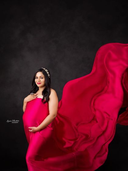 I love creating drama with tossing fabrics. Here, a vibrant red fabric flows behind the mom-to-be, creating a sense of movement and power.