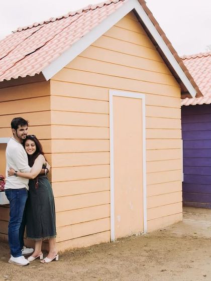 A sweet, simple hug against a row of colorful huts. This photo captures a casual and affectionate moment, showing the couple's easy comfort with each other.