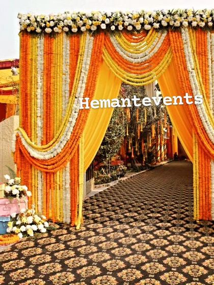 A grand entrance for a Haldi ceremony, heavily draped with orange and white marigold garlands. This traditional and opulent design makes a strong statement.