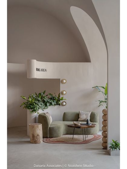 A detail of the waiting area in the "Vault's Up" project. The curved planter wall, filled with greenery, separates the space while maintaining an open, flowing feel, complemented by a soft green sofa.